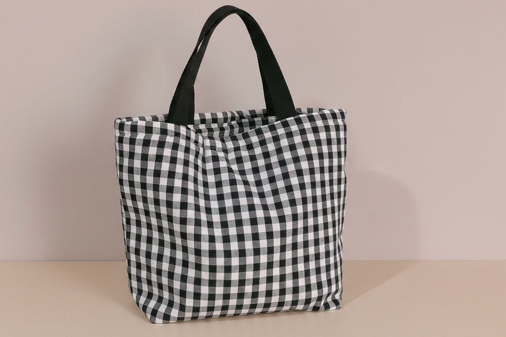 Black and white checkered tote bag on a light gray background