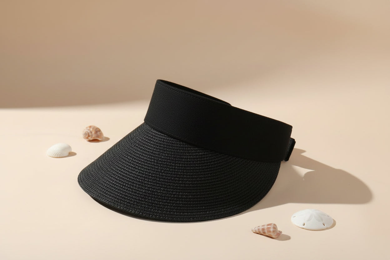 Black visor hat on a white surface with a magazine underneath