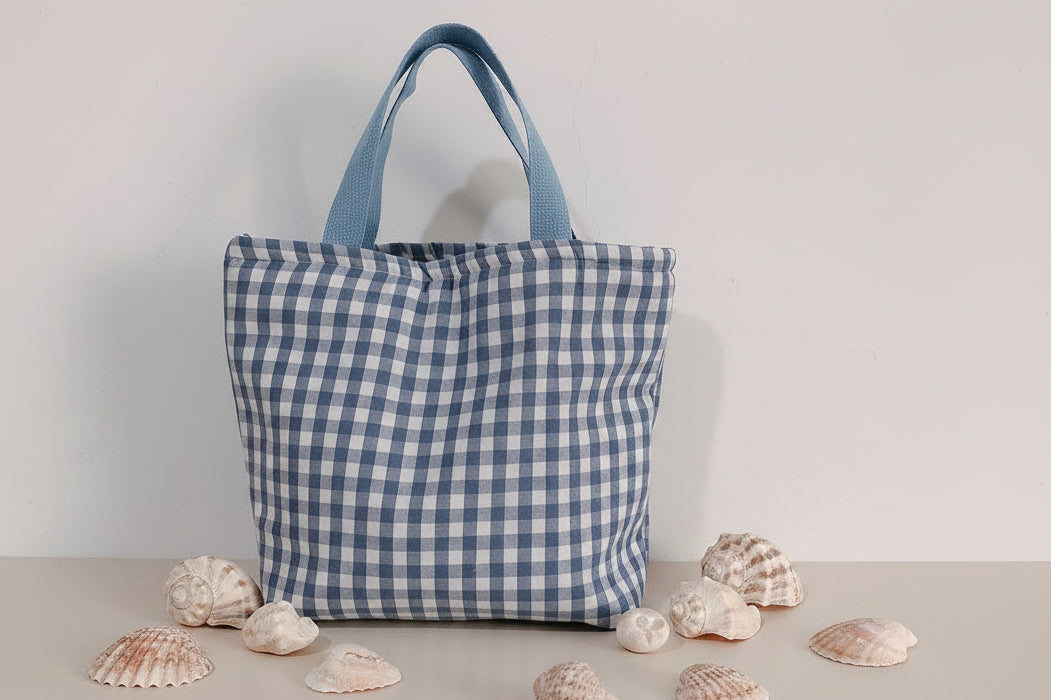Blue and white checkered tote bag  on a light surface with a neutral background