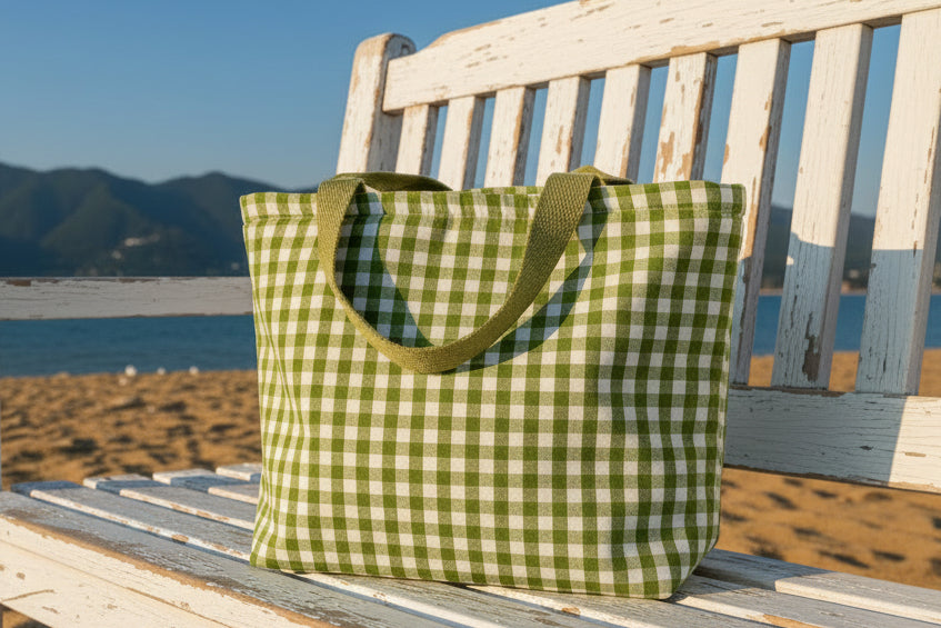 Green and white checkered bag with a handle on a light gray surface.