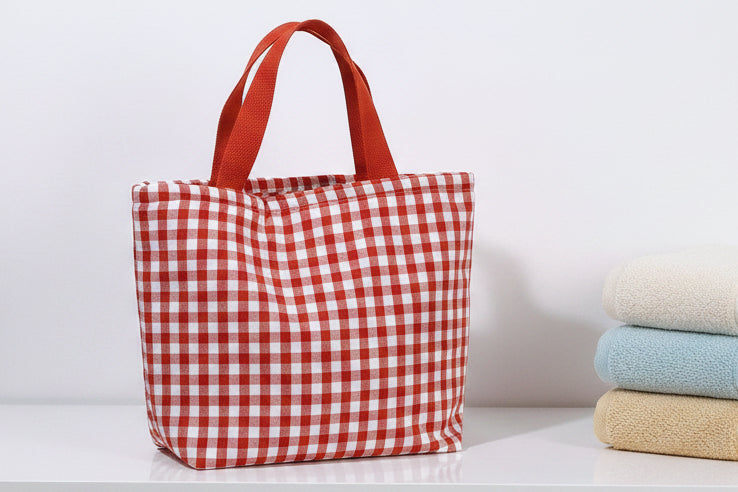 Red and white checkered tote bag on a light surface with a neutral background
