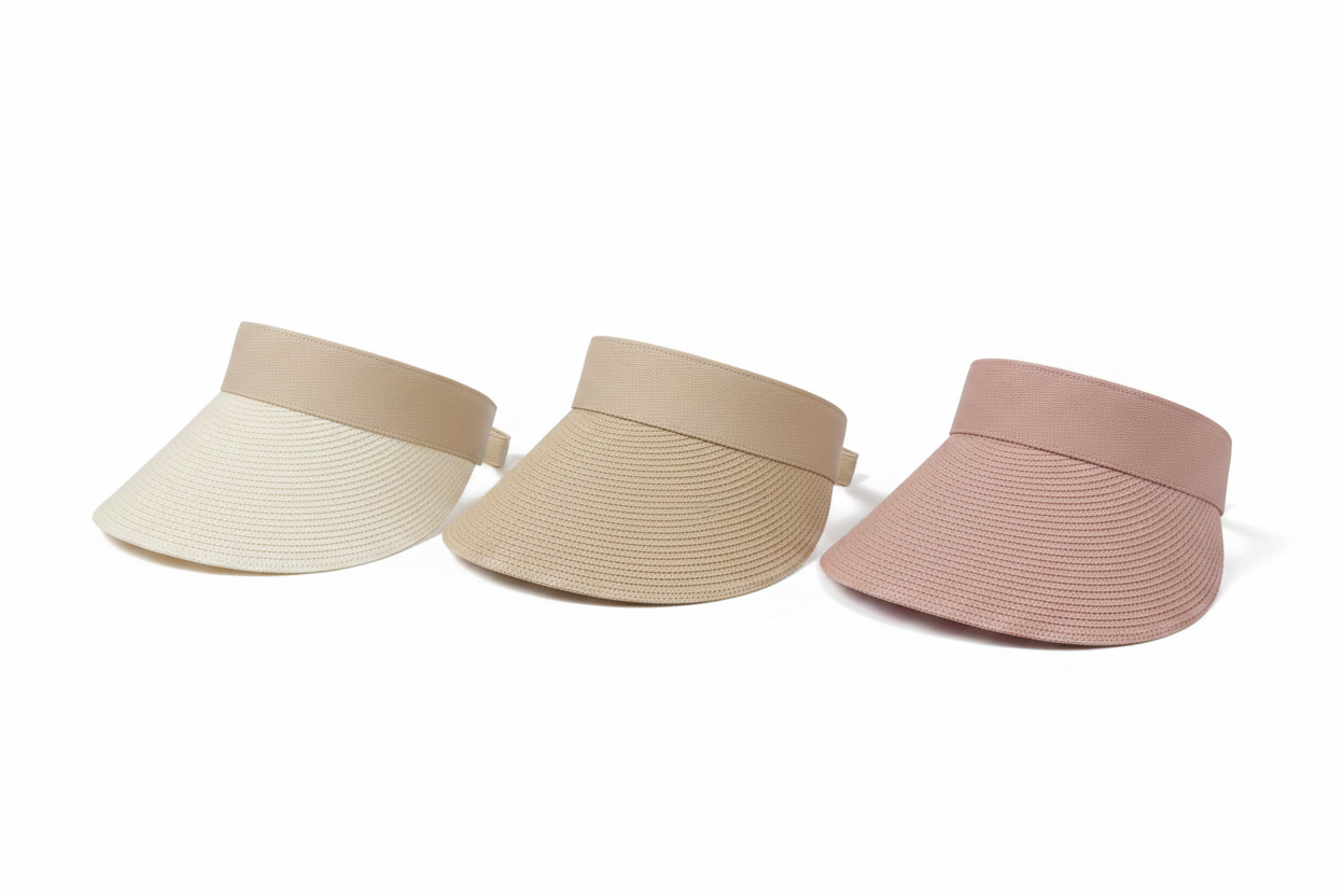 Two straw visors, one beige and one pink, on a white surface with a woven basket in the background.