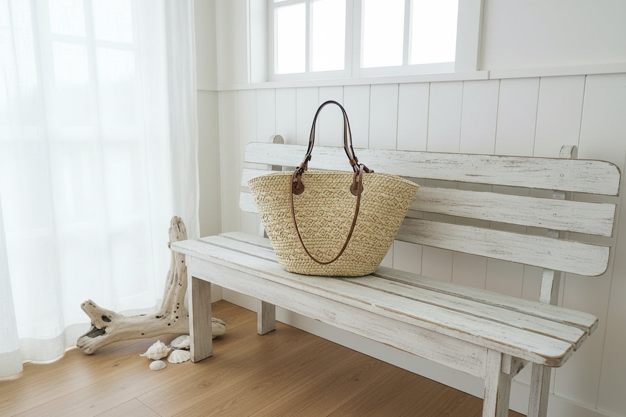 Woven handbag with brown leather straps on a black surface against a neutral background